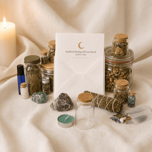 A white card with a crescent moon logo and the text 'Health & Healing Self Care Ritual Spelt Be Guide' stands upright on draped cream fabric, surrounded by jars of dried herbs, crystals, a sage bundle, a blue oil bottle, a teal candle, and a lit white pillar candle.